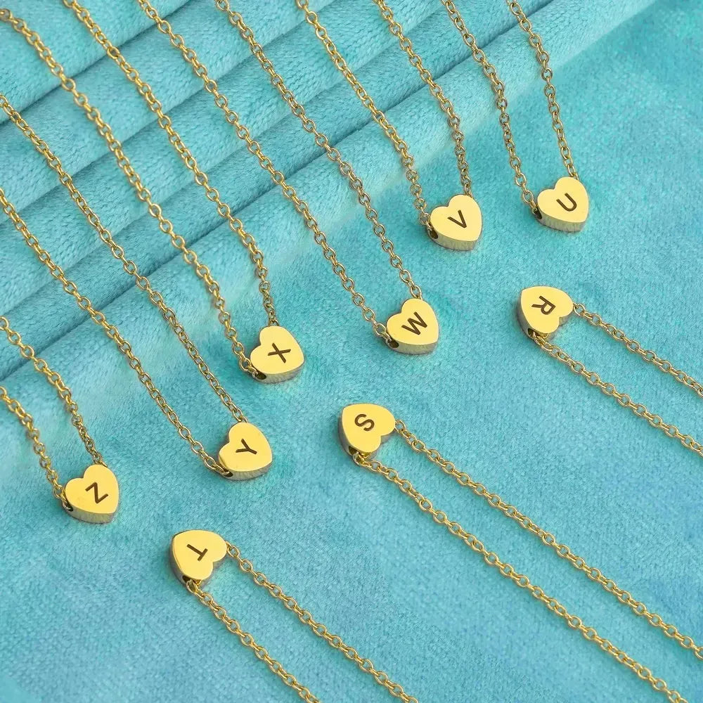 Gold necklaces with heart-shaped pendants displaying letters on a turquoise background - Affordbale artificial jewellery in pakistan