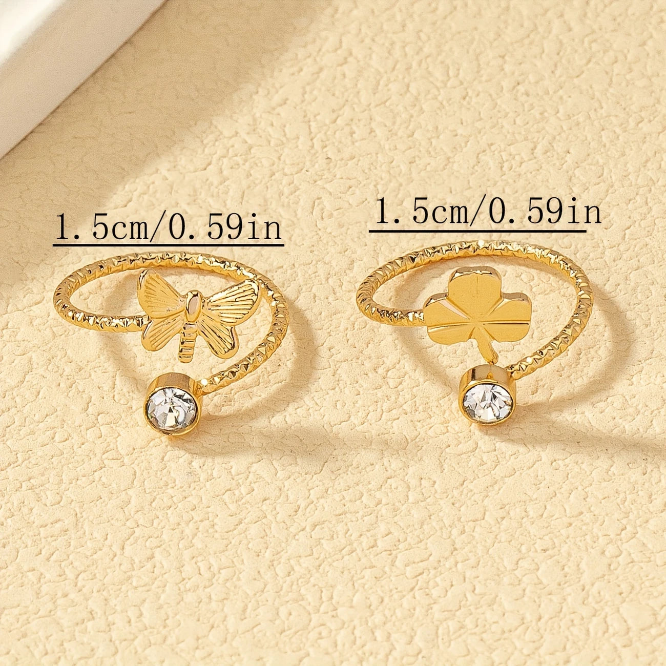 Two gold rings with butterfly and clover designs on a beige background - Affordable Artificial jewellery in pakistan
