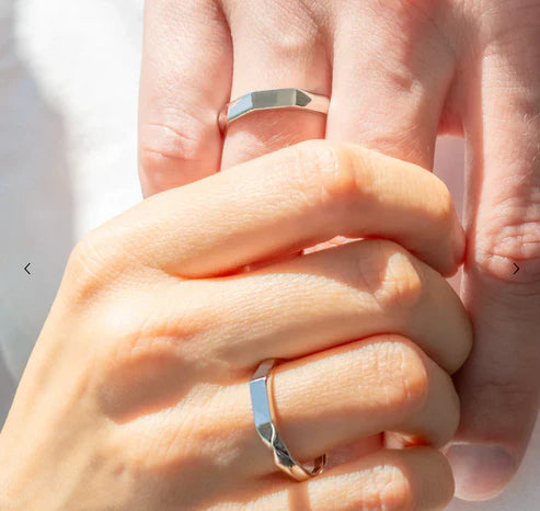 Close-up of two hands wearing silver rings with a blurred background