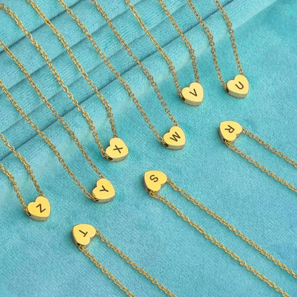 Gold necklaces with heart-shaped pendants displaying letters on a turquoise background - Affordbale artificial jewellery in pakistan