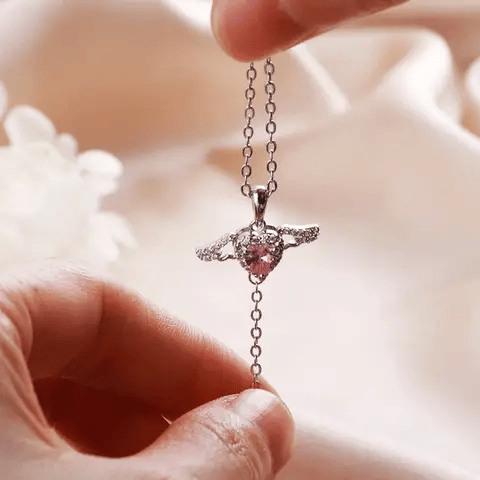 Flying Angel Necklace with a pink gemstone held by a hand against a soft background - Affordable artificial jewellery in pakistan