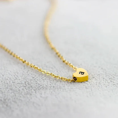 Gold heart-shaped necklace with a letter 'a' on a light gray background - Affordbale artificial jewellery in pakistan