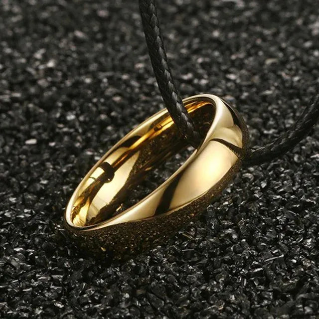 Gold ring pendant on a black cord against a dark textured background - Affordable artifiial jewellery in pakistan