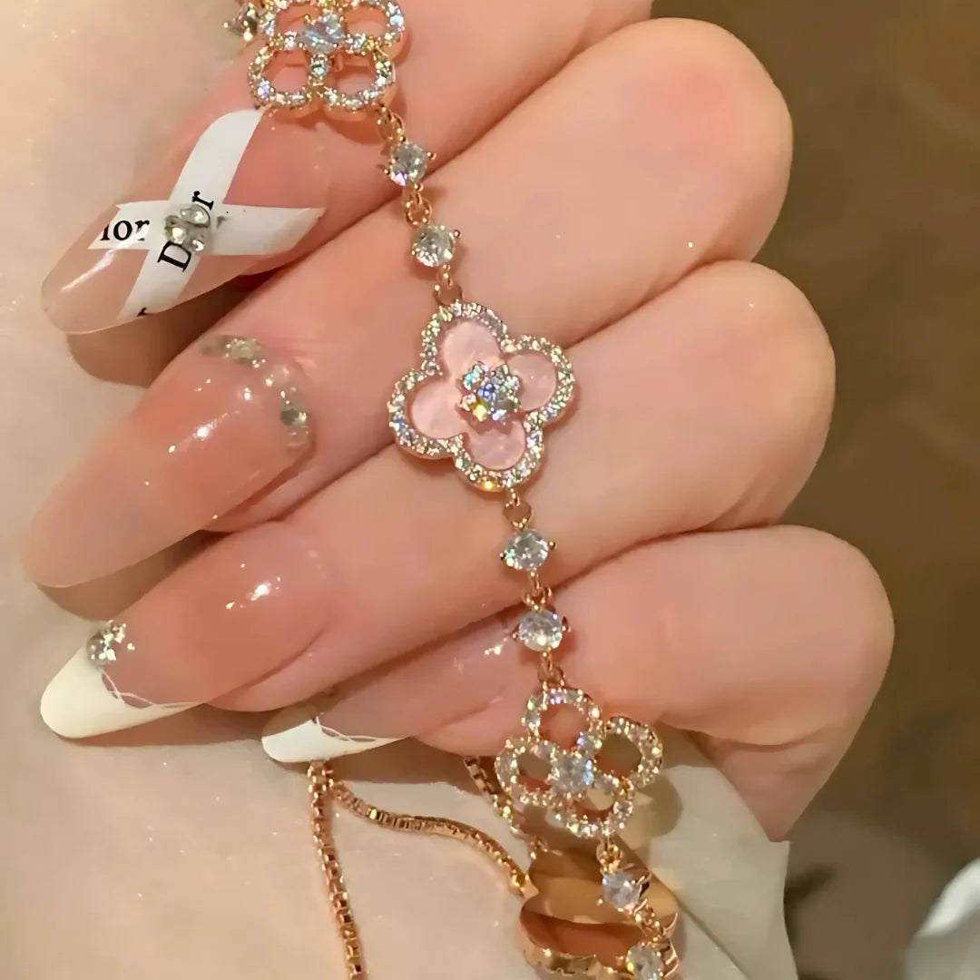 Decorative hand chain with floral designs held by a person with manicured nails.