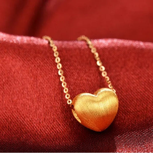 Gold heart-shaped pendant necklace on a red fabric background