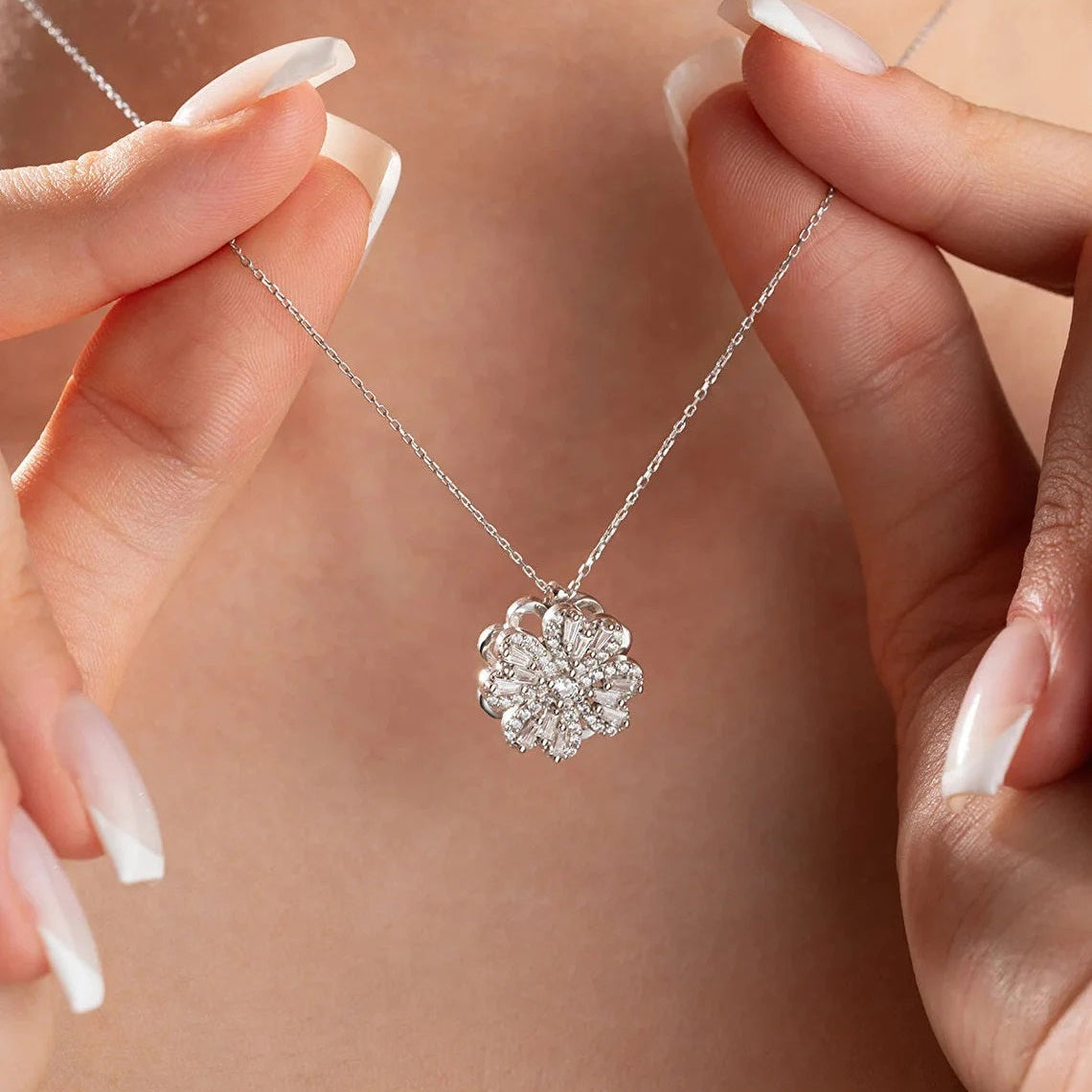 Lucky Clover Spinner Silver necklace with a floral pendant held by hands against a neutral background