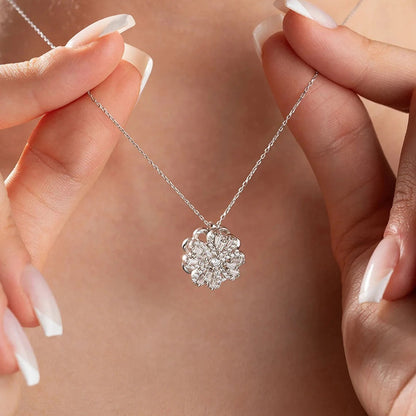 Lucky Clover Spinner Silver necklace with a floral pendant held by hands against a neutral background