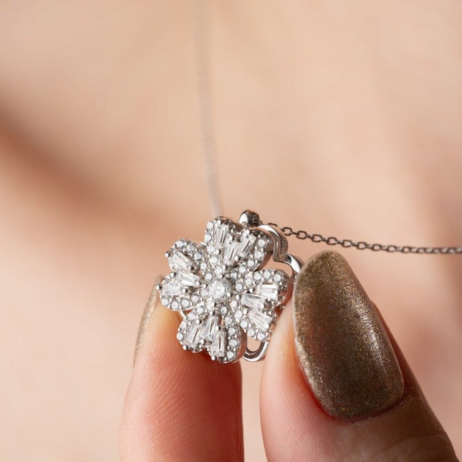 Lucky Clover Spinner Necklace held by a hand with a blurred background