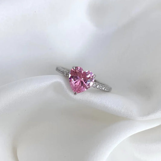 Heart-shaped pink gemstone ring on a white fabric background