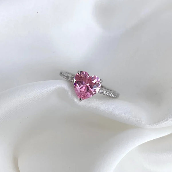 Heart-shaped pink gemstone ring on a white fabric background