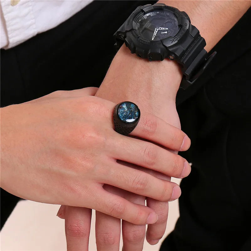 Person wearing a black watch and ring on a neutral background