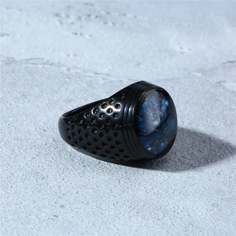 Black ring with blue stone on a textured gray surface