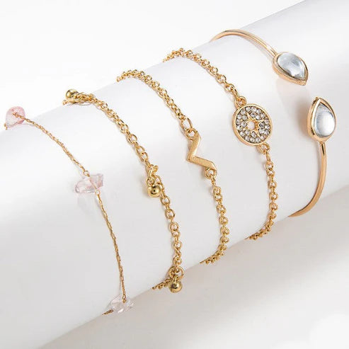 Set of gold bracelets with various designs on a white surface