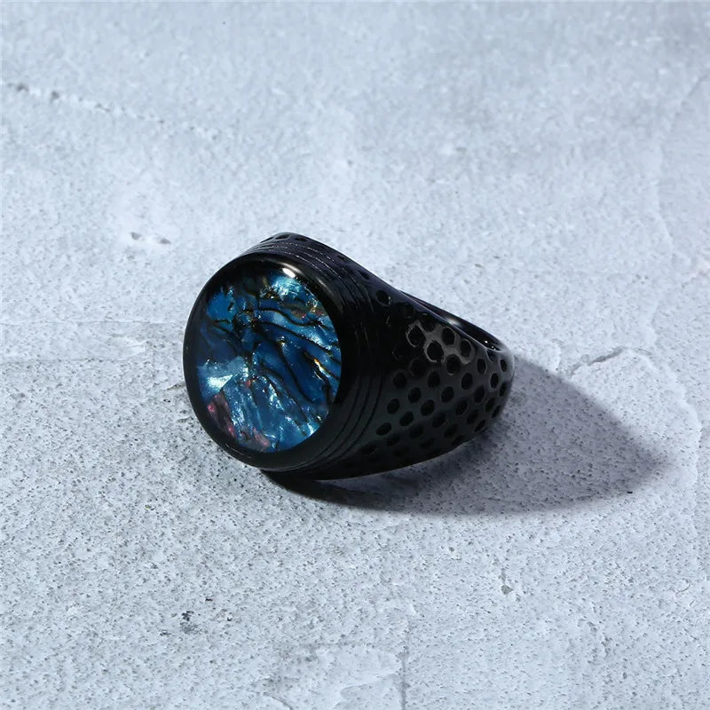 Black ring with blue gemstone on a textured gray surface