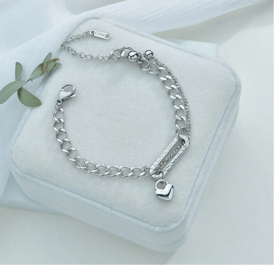 Silver chain bracelet with a heart charm on a white box with a white background