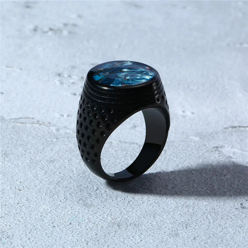 Black ring with blue gemstone on a textured surface