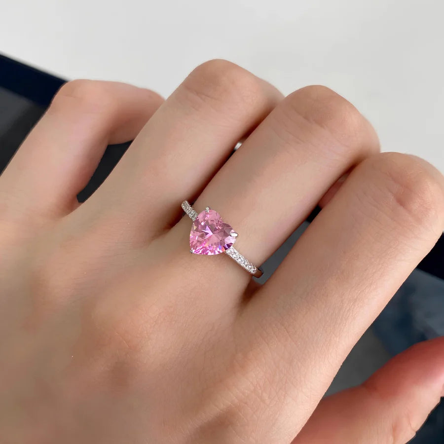 Pink gemstone ring on a hand against a neutral background