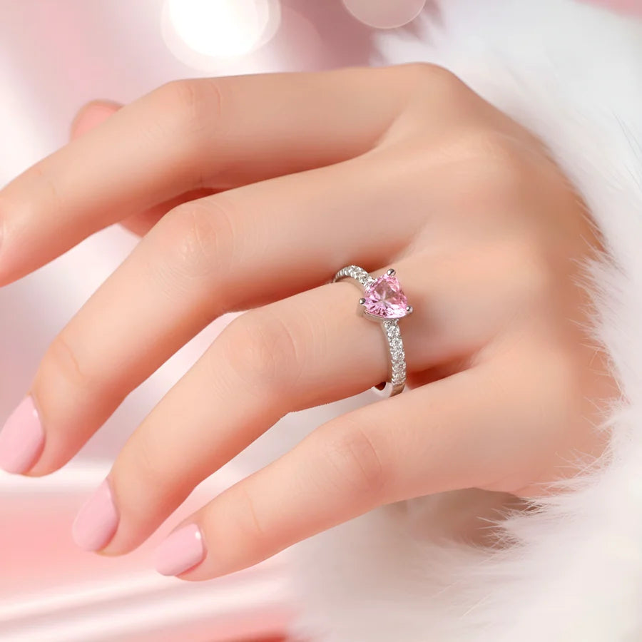 Hand wearing a pink gemstone ring on a soft pink background
