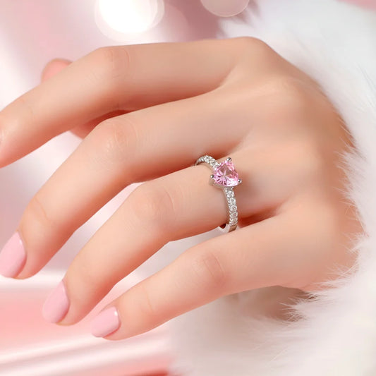Hand wearing a pink gemstone ring on a soft pink background