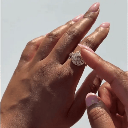 Close-up of two hands with a Radiant Daisy Flower Spinner ring on a light background