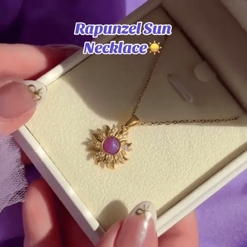 Gold necklace with a purple pendant in a box, labeled 'Rapunzel Sun Necklace'.