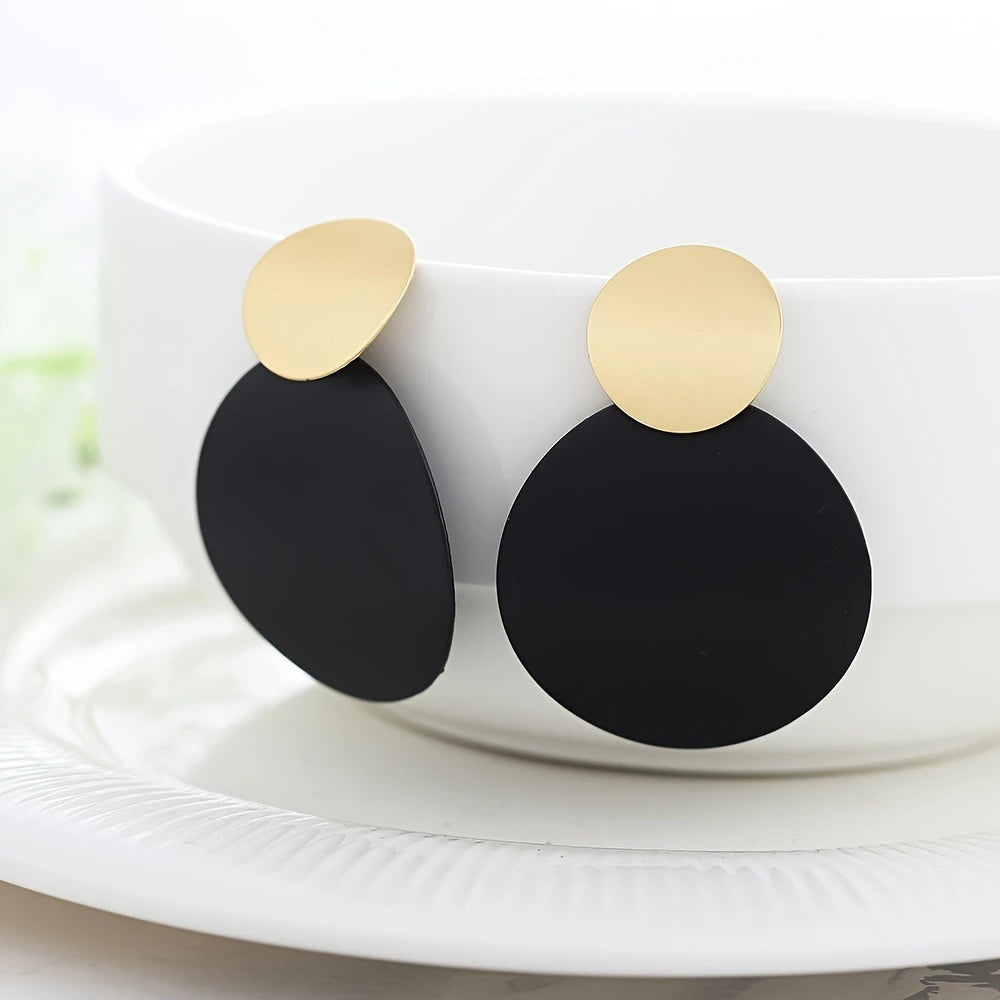 Black earrings with gold accents on a white surface - part of affordable artificial jewellery in Pakistan