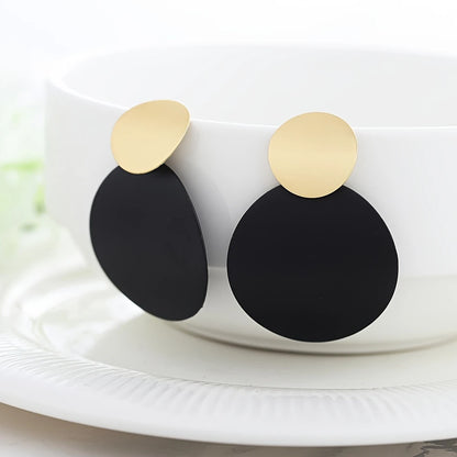 Black earrings with gold accents on a white surface - part of affordable artificial jewellery in Pakistan