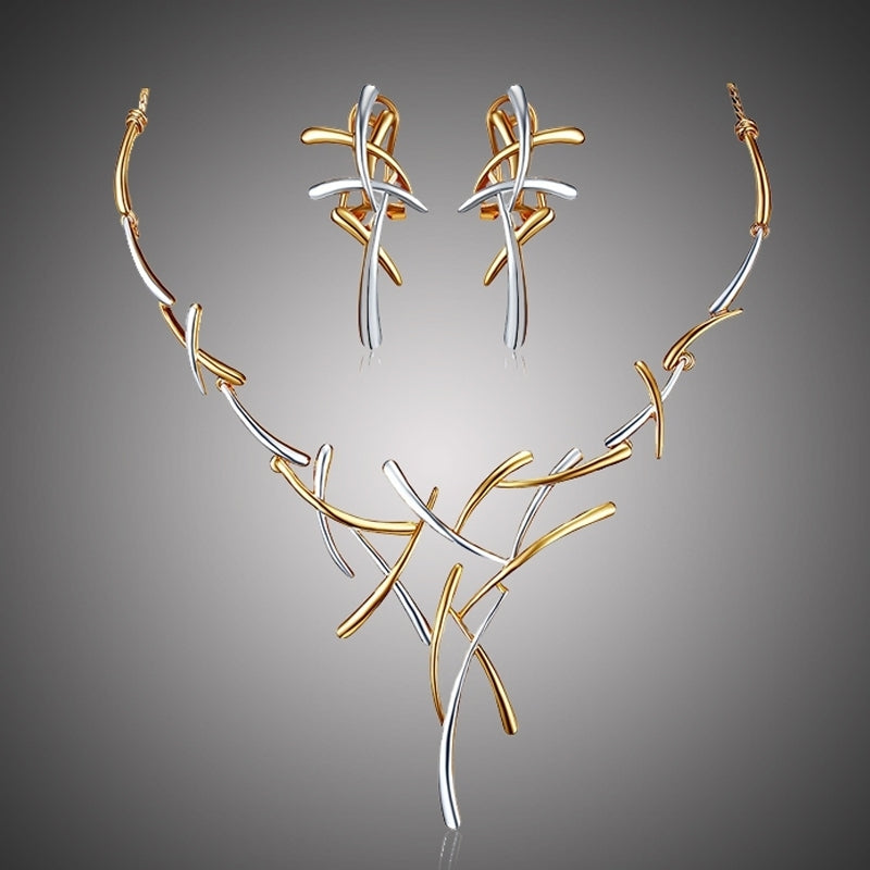 Jewelry set with gold and silver necklace and earrings on a gray background