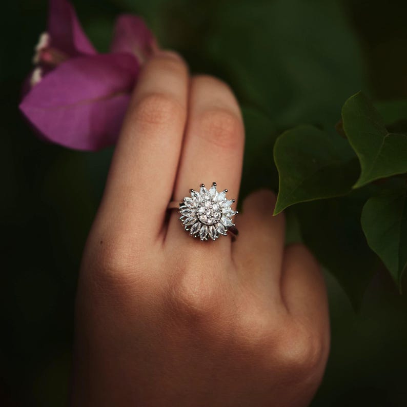 Silver ring with a diamond design on a hand against a natural background