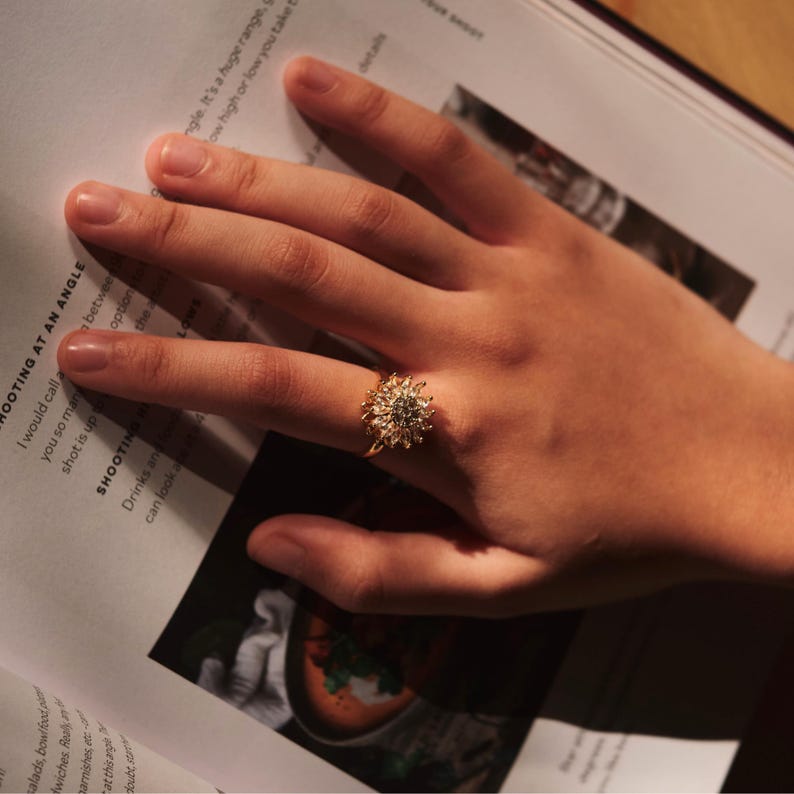 Hand wearing a gold ring with a diamond on a magazine page