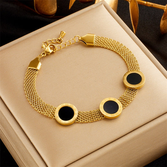 Gold bracelet with black stones on a beige jewelry box
