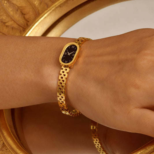 Gold watch on a wrist with a decorative gold frame in the background