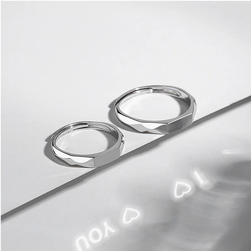 Two silver rings on a reflective surface with a light gray background