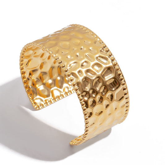 Gold bracelet with intricate design on a white background