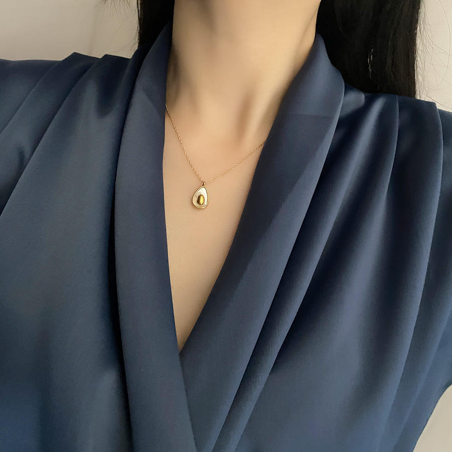 Gold necklace with a pendant worn by a person in a blue outfit.