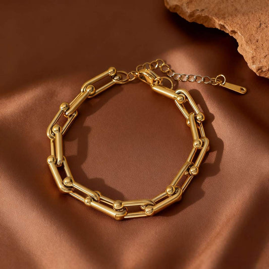 Gold chain bracelet on a brown fabric background