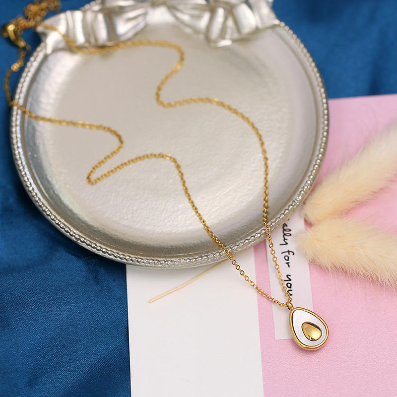 Gold necklace with a pendant on a decorative dish with a blue and pink background