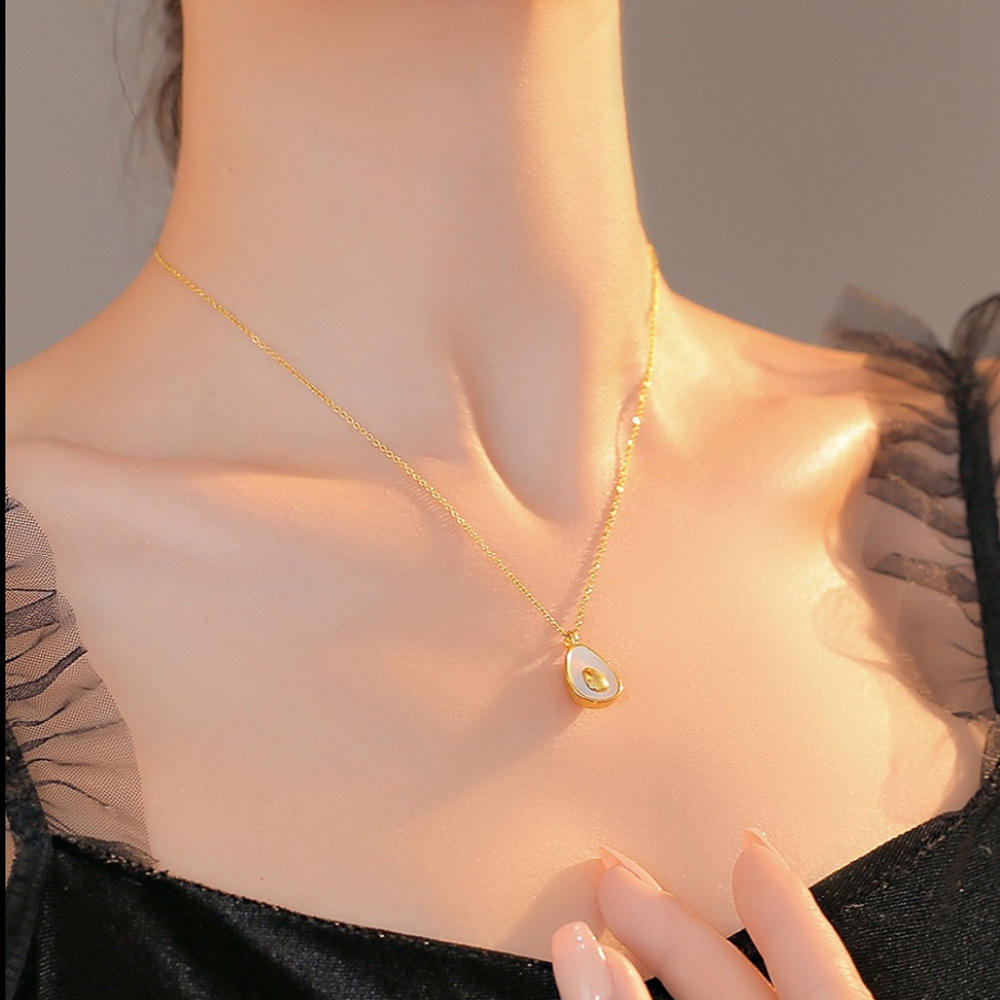 Gold necklace with a pendant on a person wearing a black top.