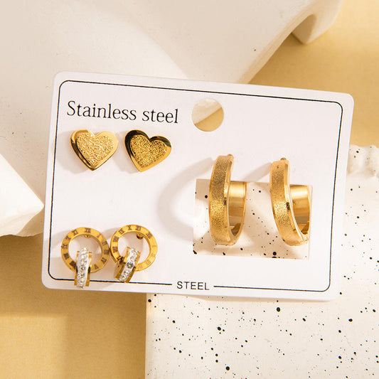 Set of gold earrings on a branded card with 'Stainless steel' text.