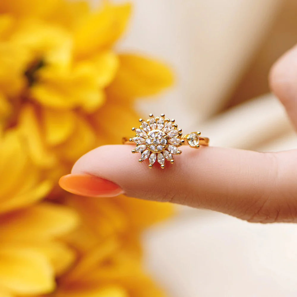 Gold ring with diamonds on a finger against a yellow floral background