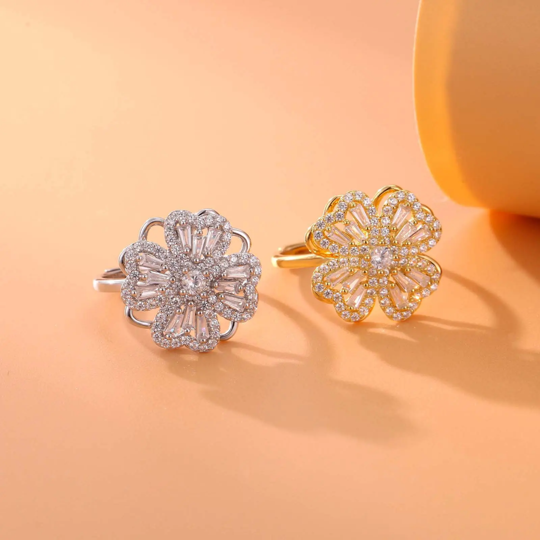 Two floral rings, one silver and one gold, on a peach background
